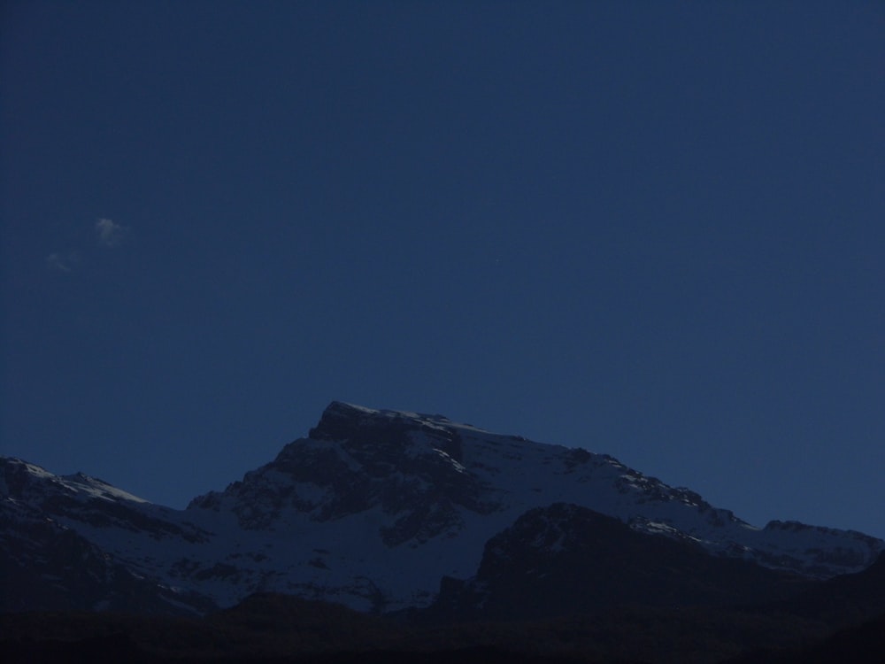 the moon is setting over a snowy mountain
