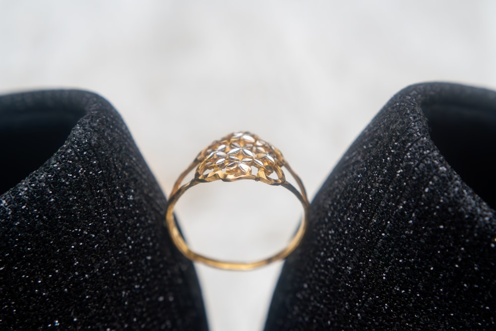 a gold ring sitting on top of a pair of black shoes