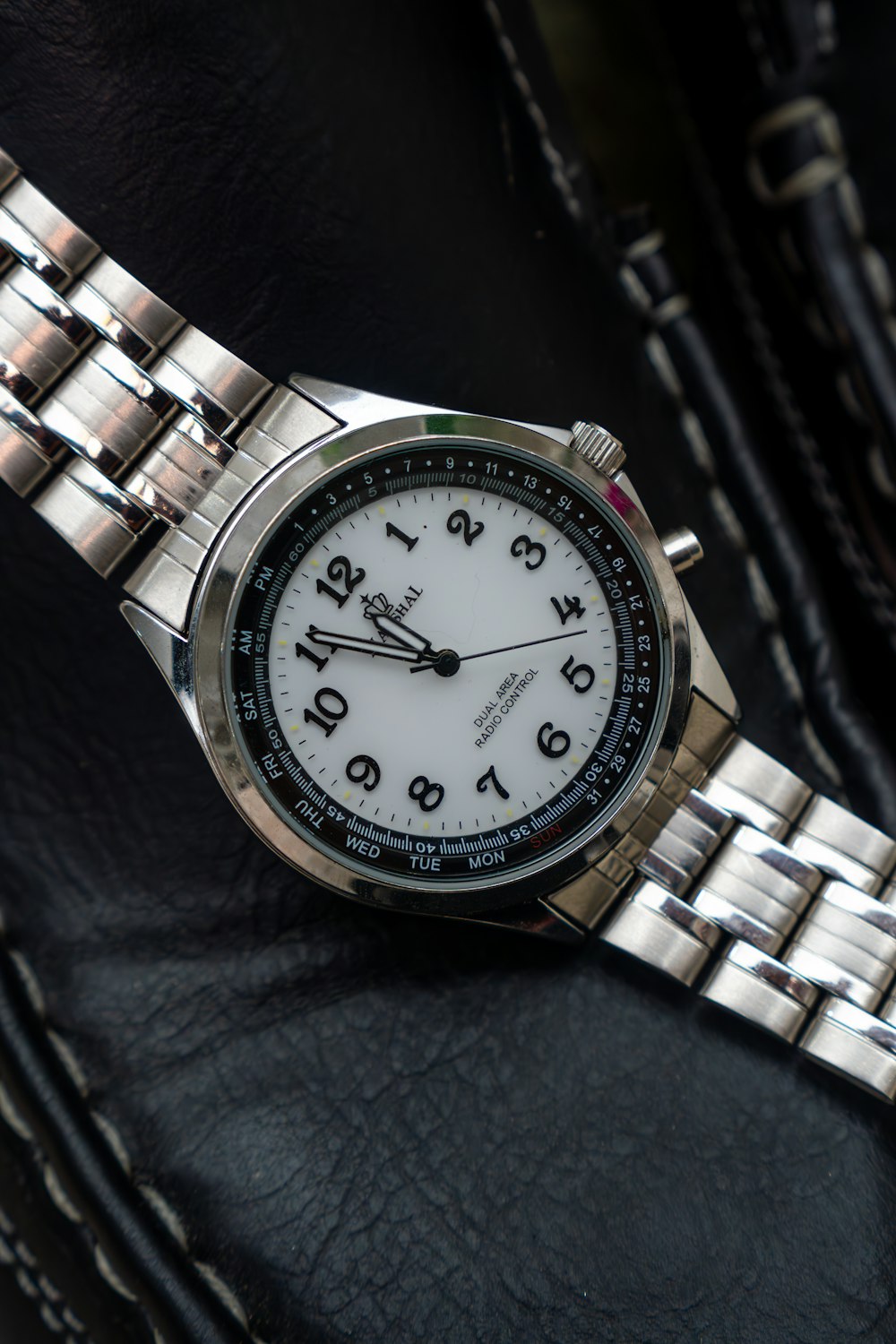a close up of a watch on a black leather surface