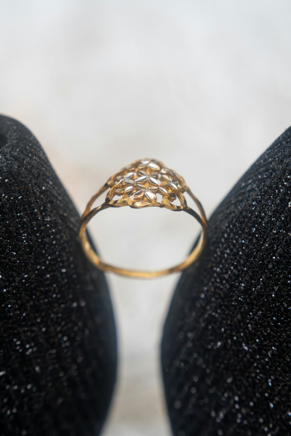 a gold ring sitting on top of a pair of black shoes