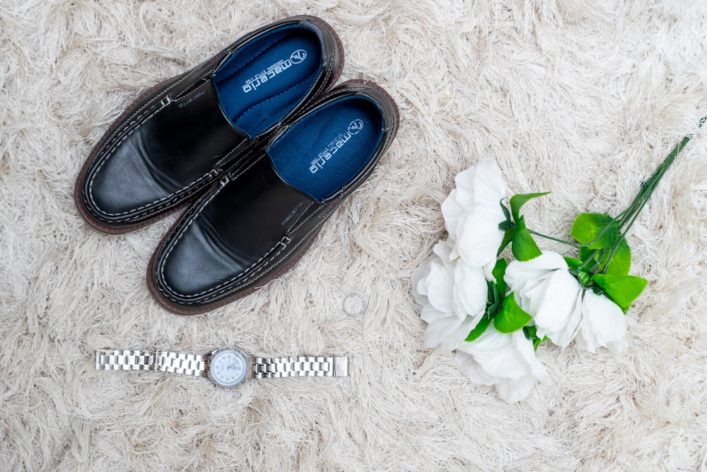 a pair of black shoes next to a white flower