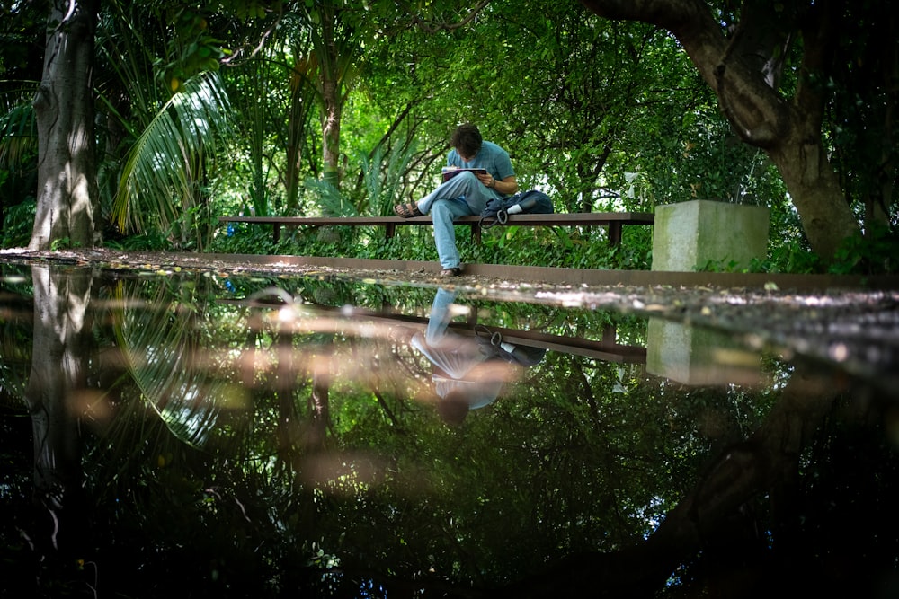 Un hombre sentado en un banco junto a un cuerpo de agua