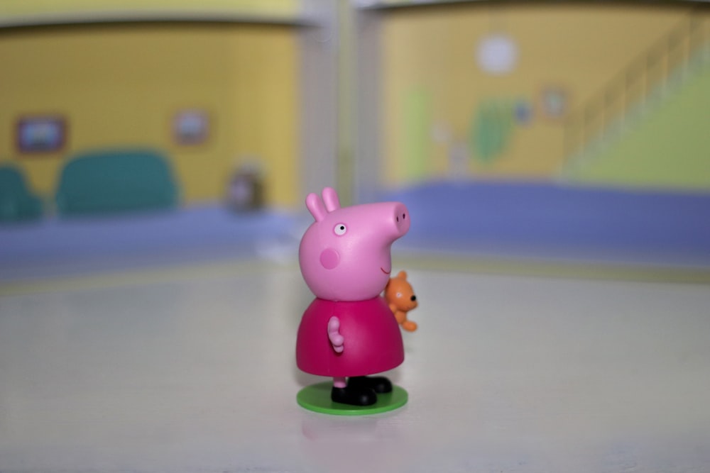 a toy pig holding a carrot on a table