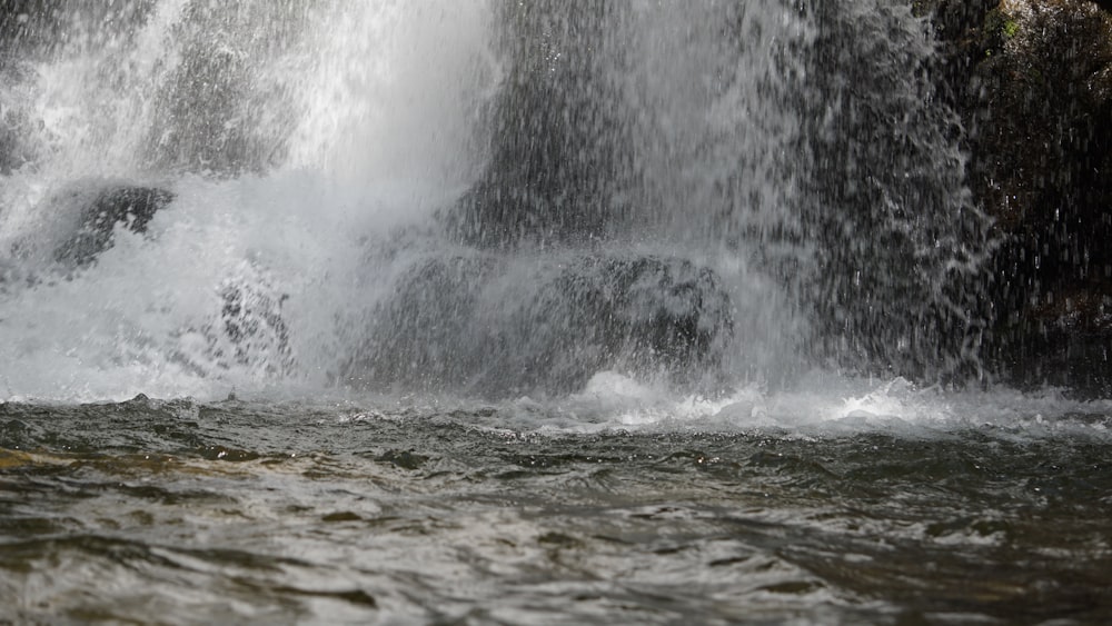 a man standing in the water next to a waterfall