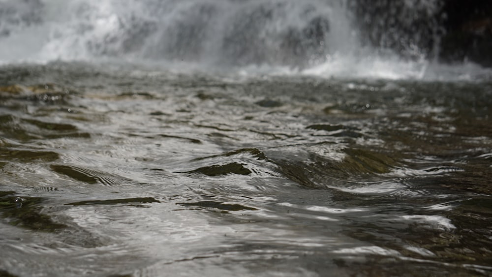 a close up of water with a waterfall in the background