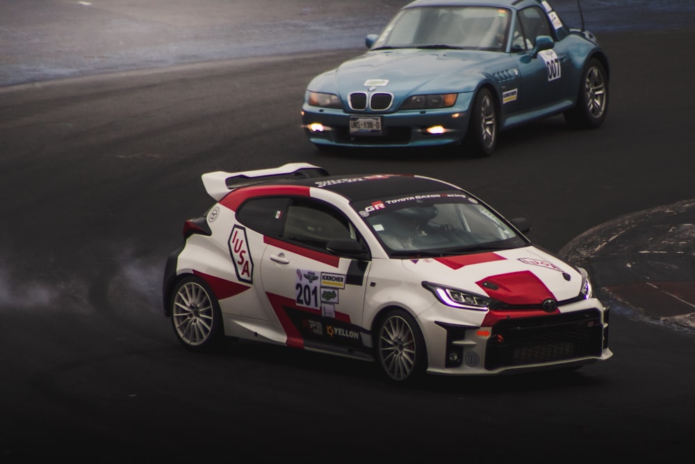 two cars on a race track with smoke coming out of the tires