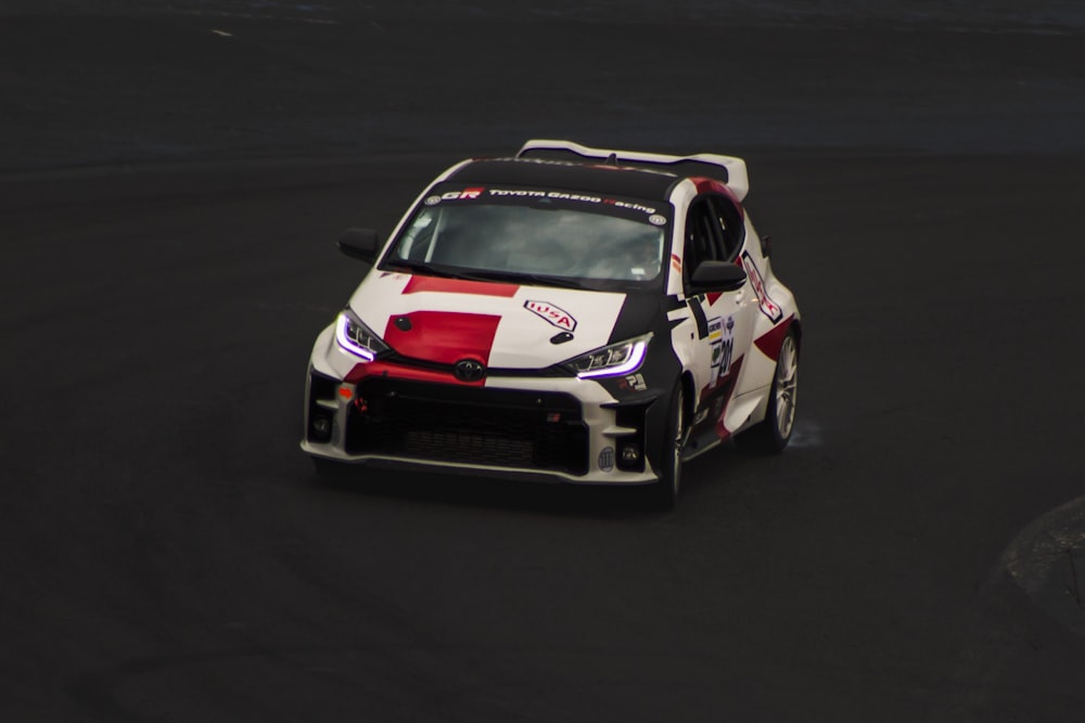 a white and red car driving on a race track