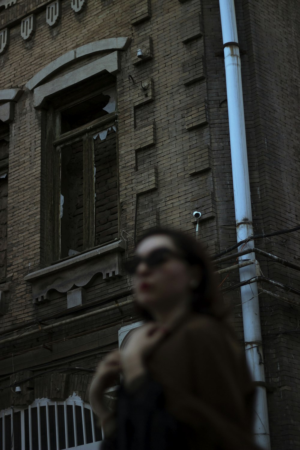 a woman standing in front of a brick building