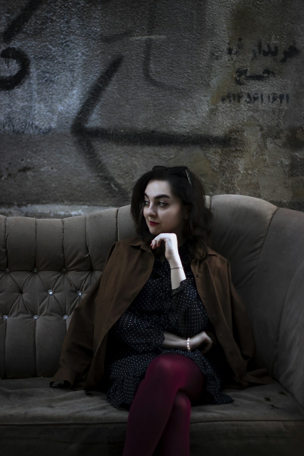 a woman sitting on top of a couch next to a wall