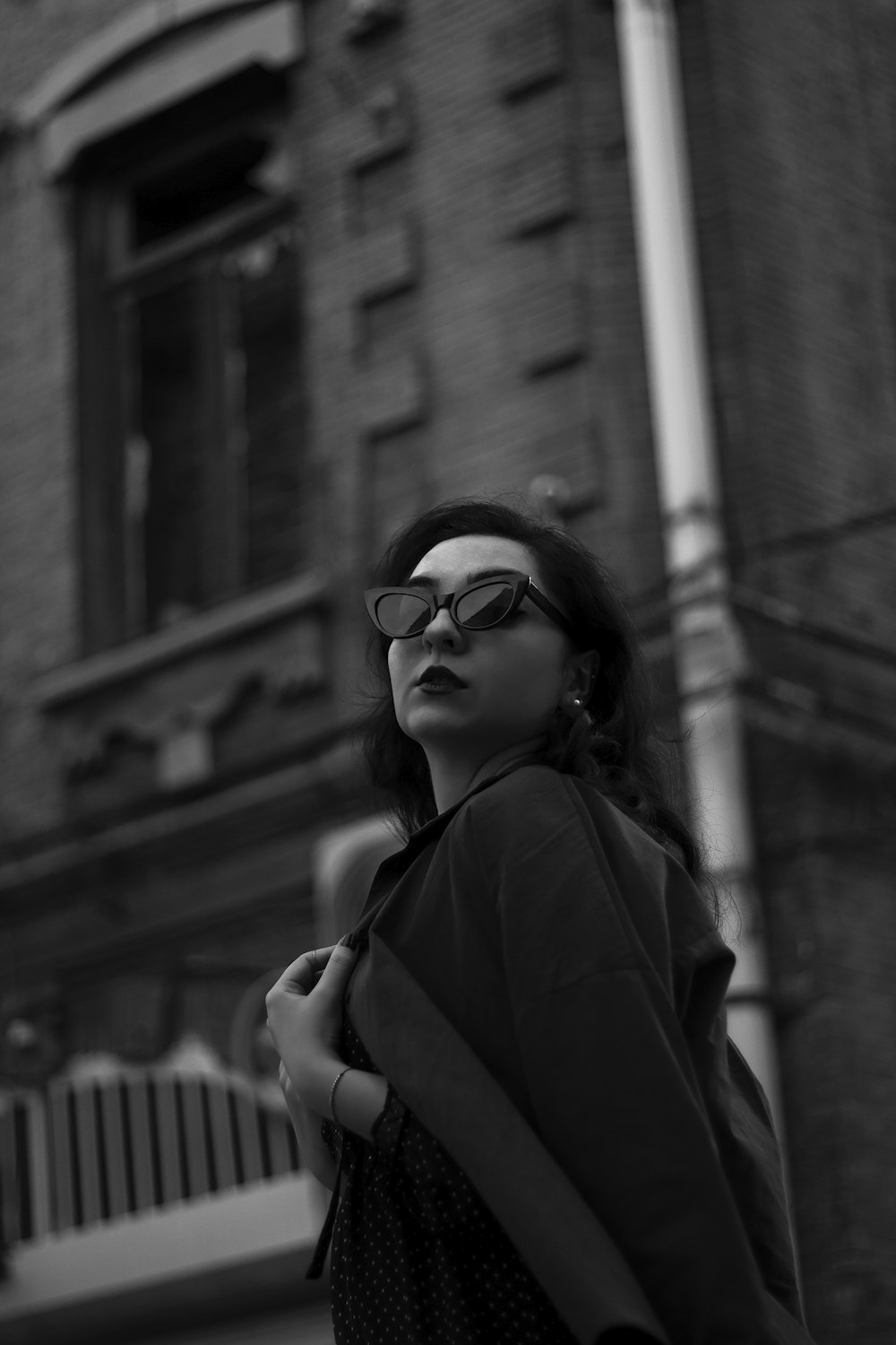a woman wearing glasses standing in front of a building