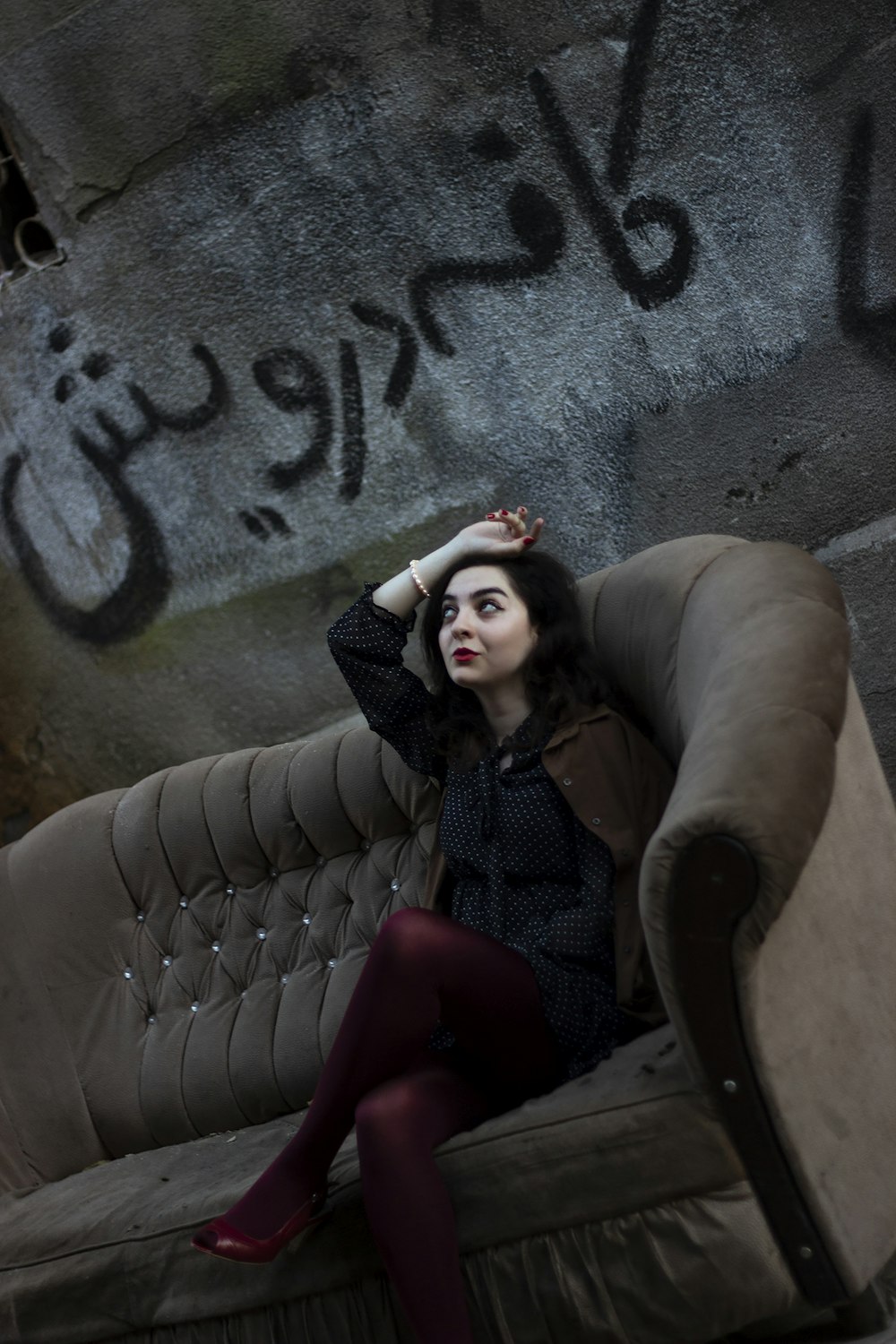 a woman sitting on top of a couch next to a wall