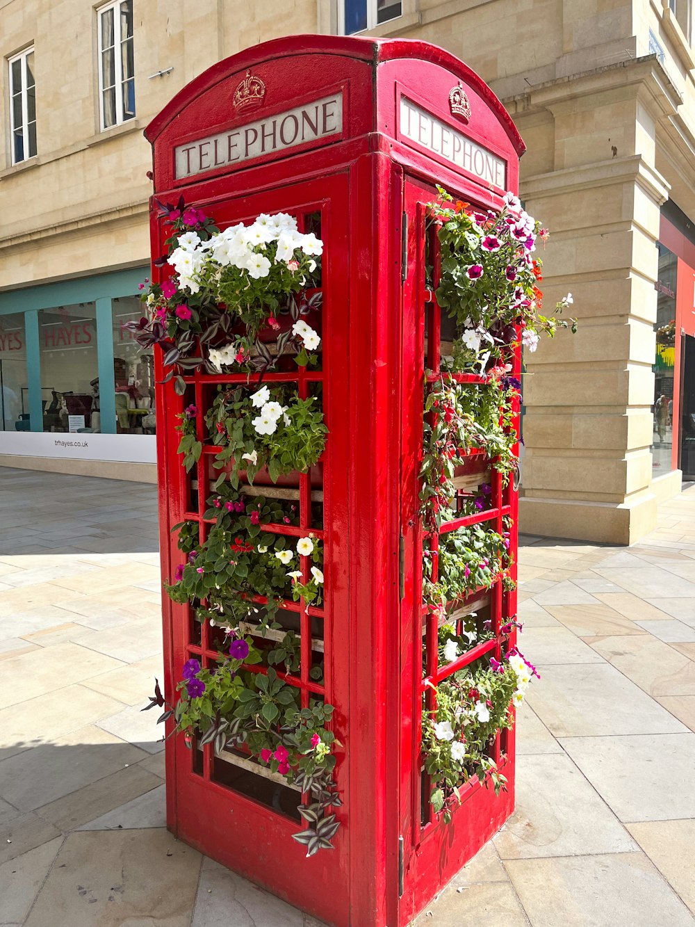 a red phone booth with flowers growing out of it