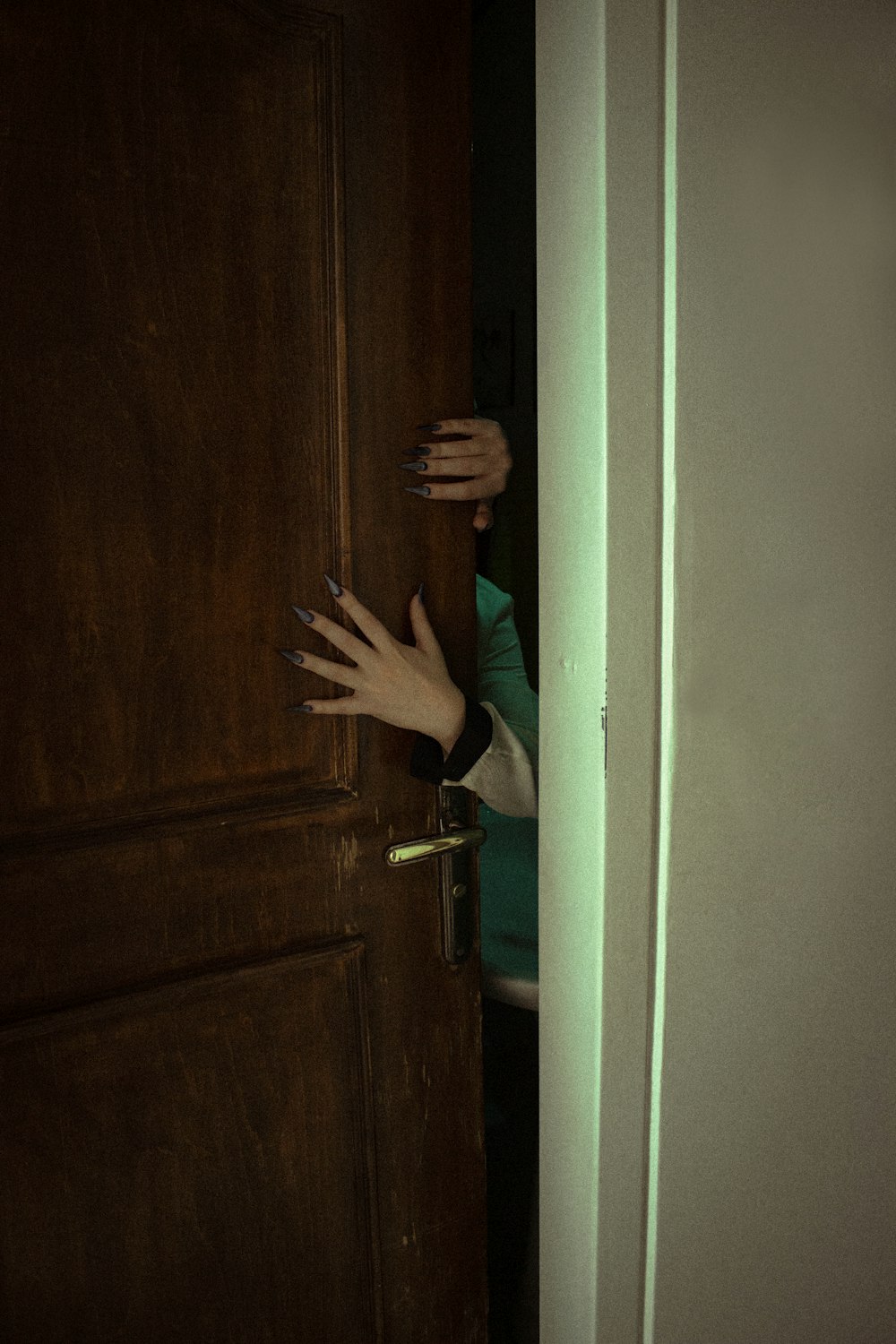 a person reaching out from behind a door