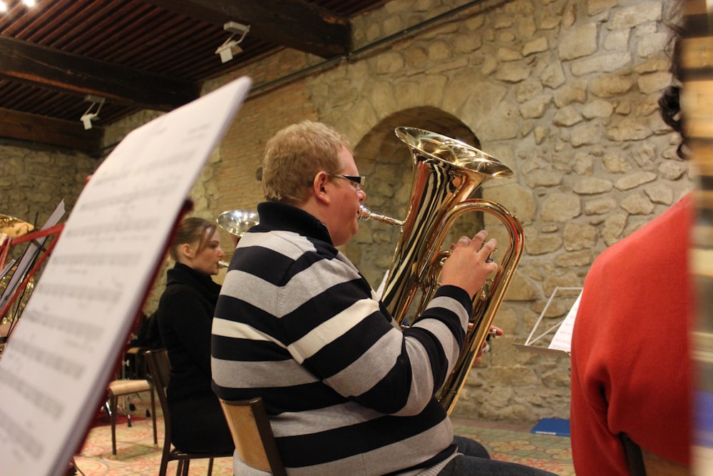 a man sitting in a chair playing a brass instrument