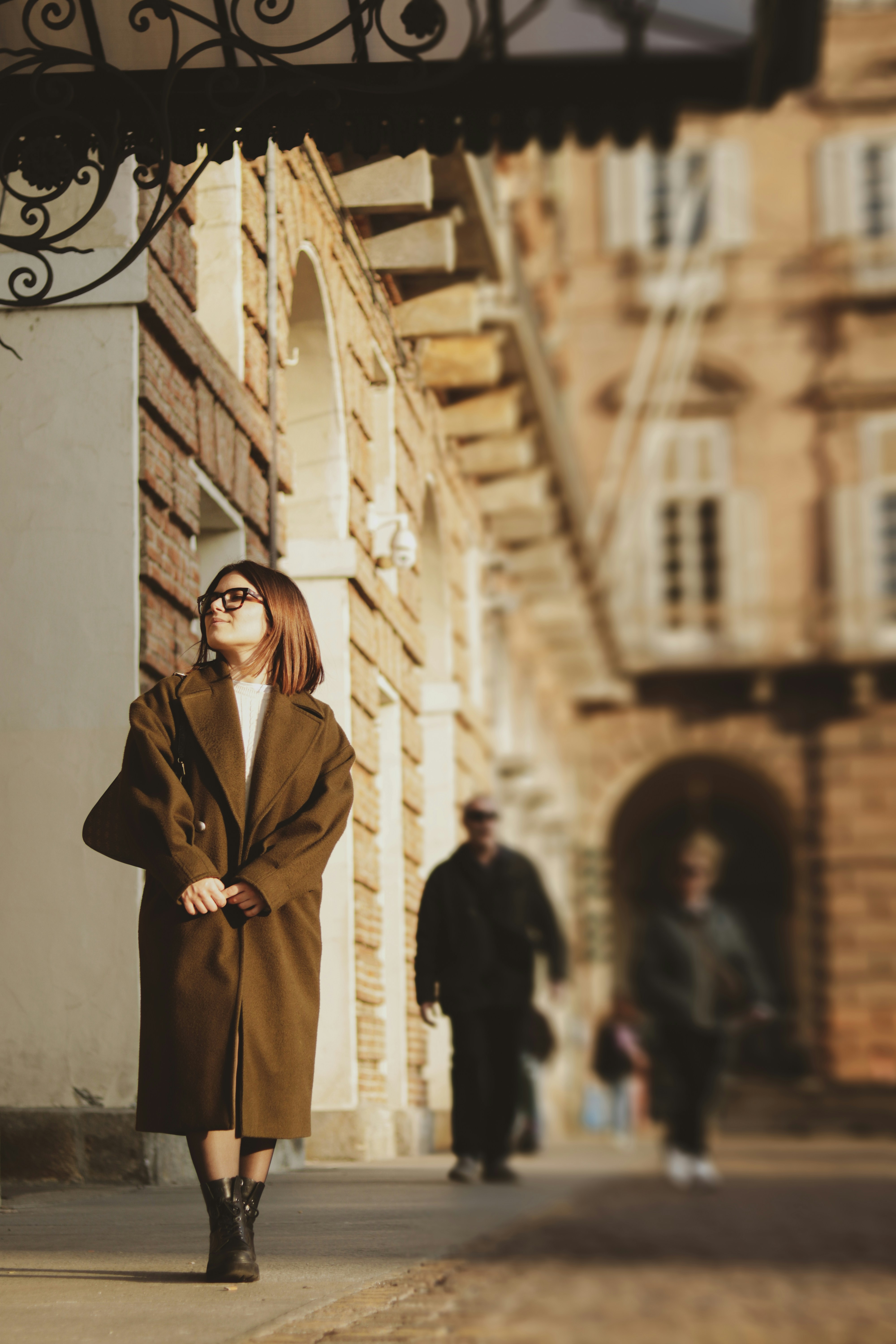 a woman in a brown coat is walking down the street