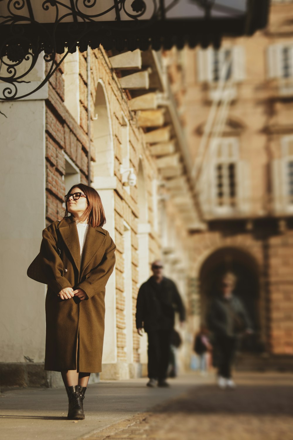 a woman in a brown coat is walking down the street