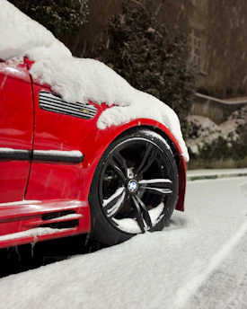 a red car covered in snow on a road