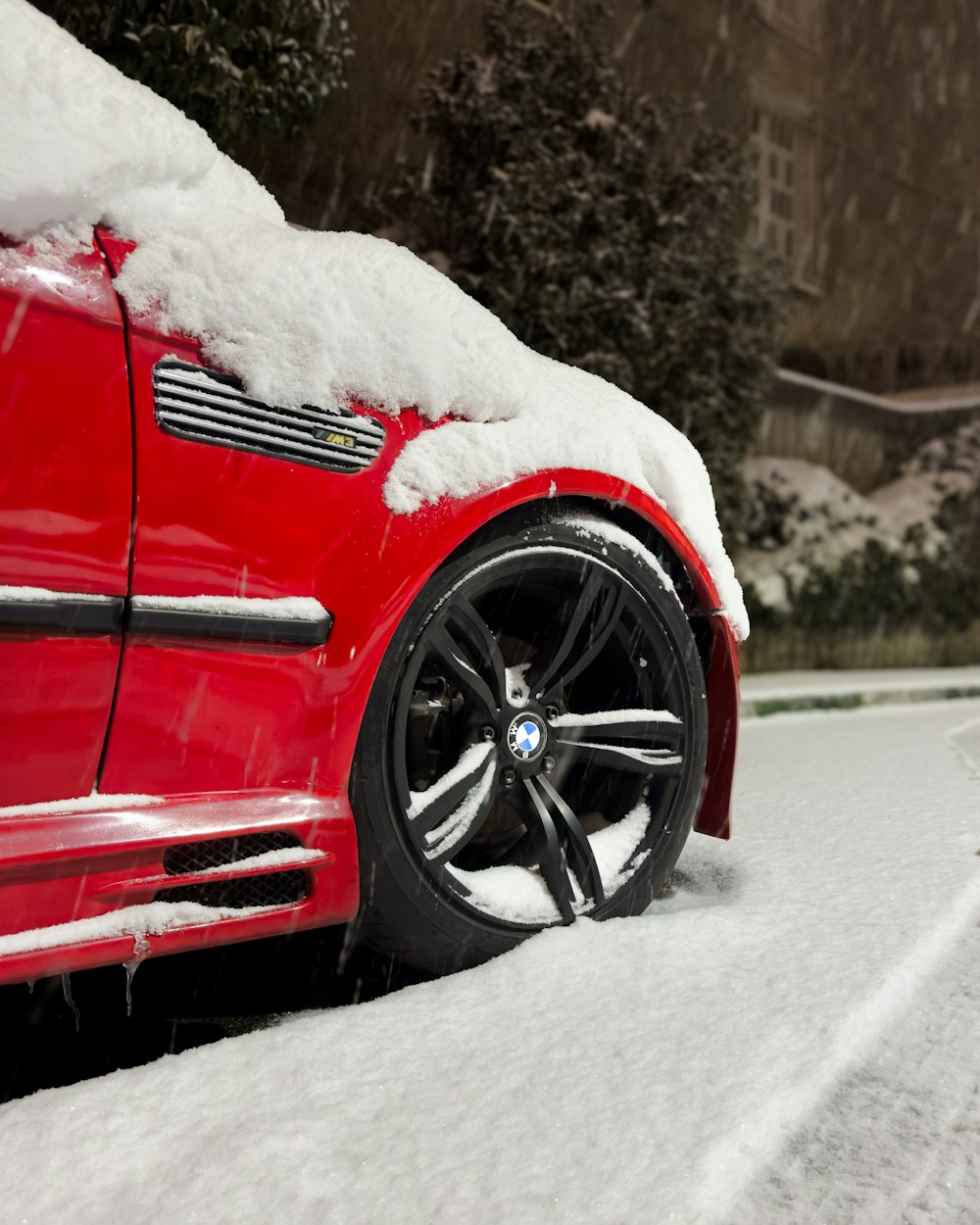 a red car covered in snow on a road