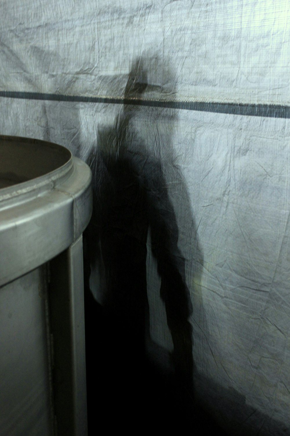 a shadow of a person standing next to a wall