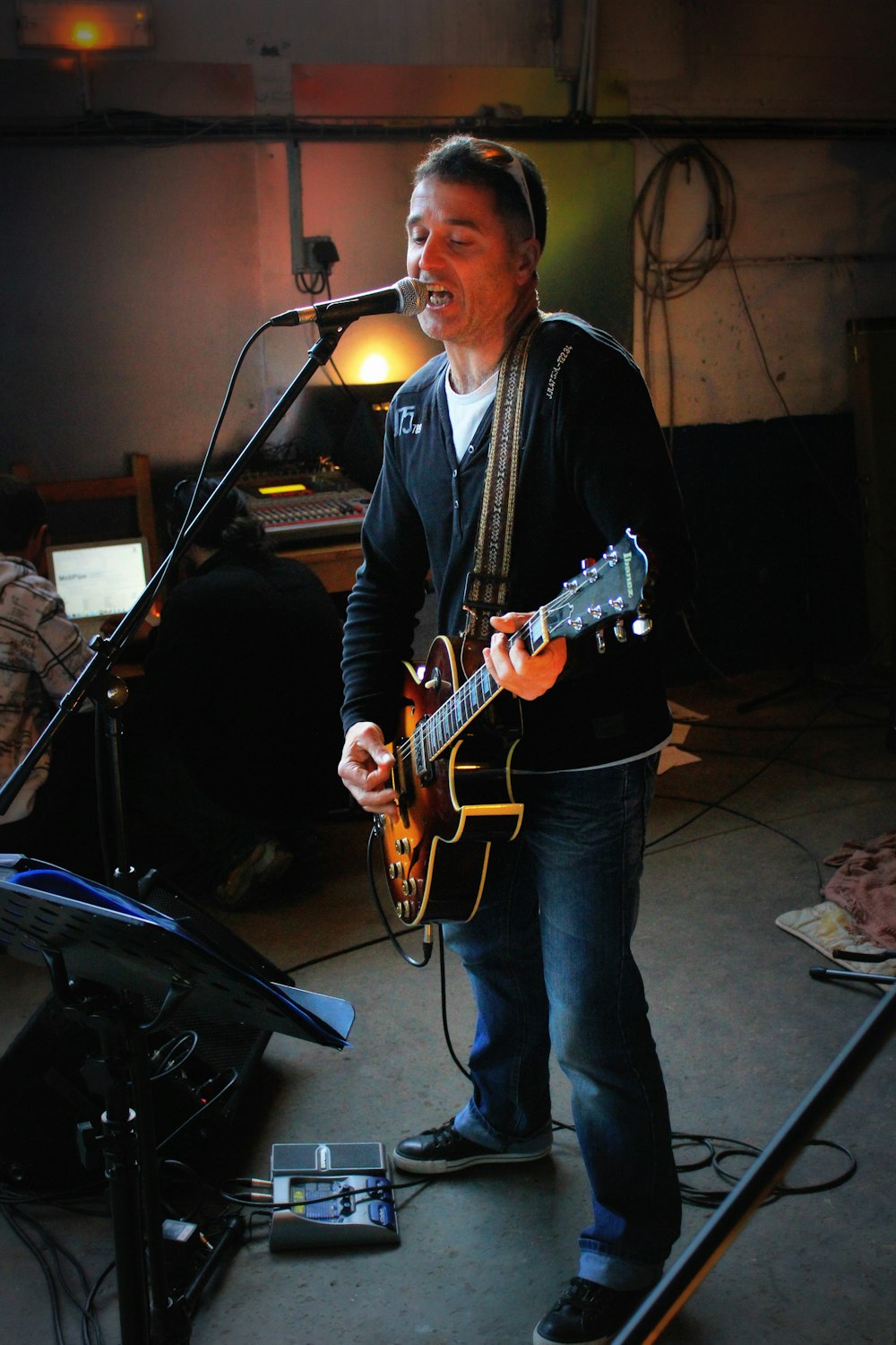 a man playing a guitar in front of a microphone