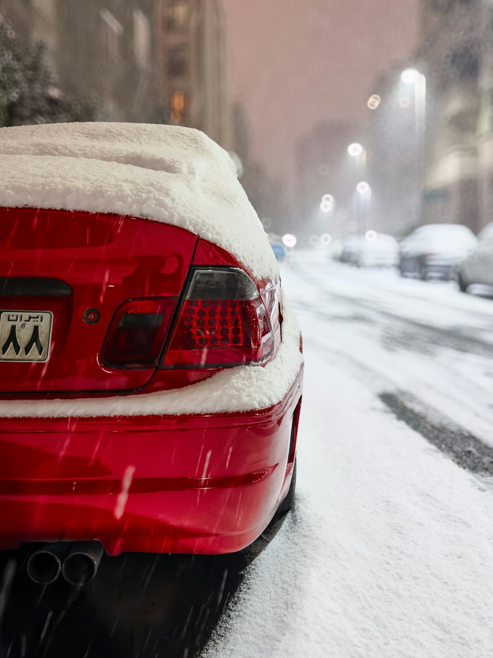 a red car covered in snow on a city street