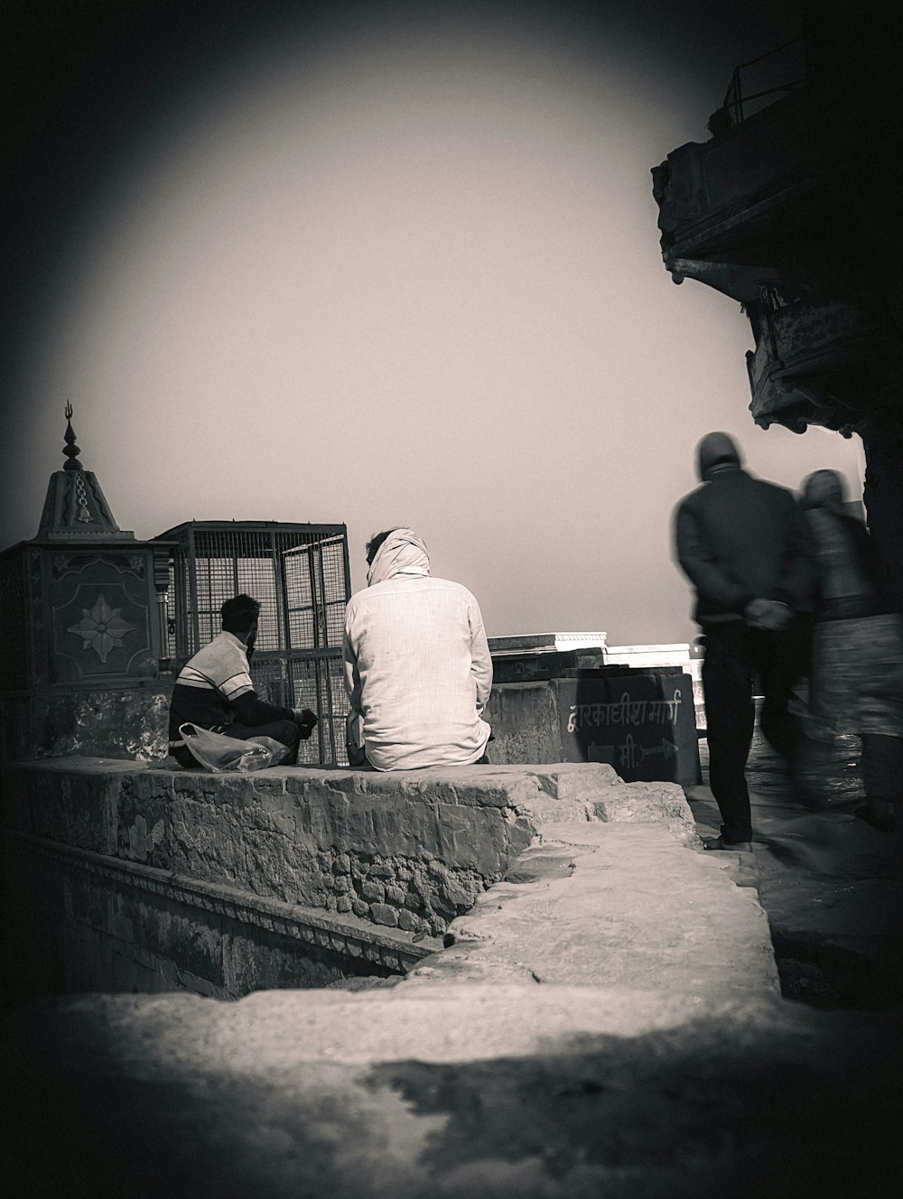 a group of people sitting on top of a stone wall