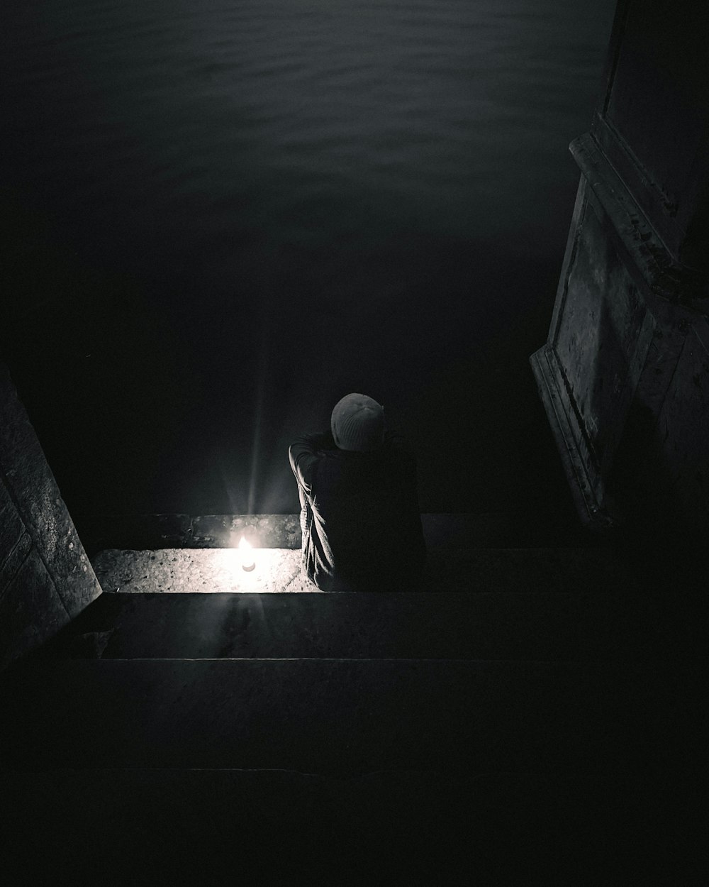 a person sitting on a ledge in the dark