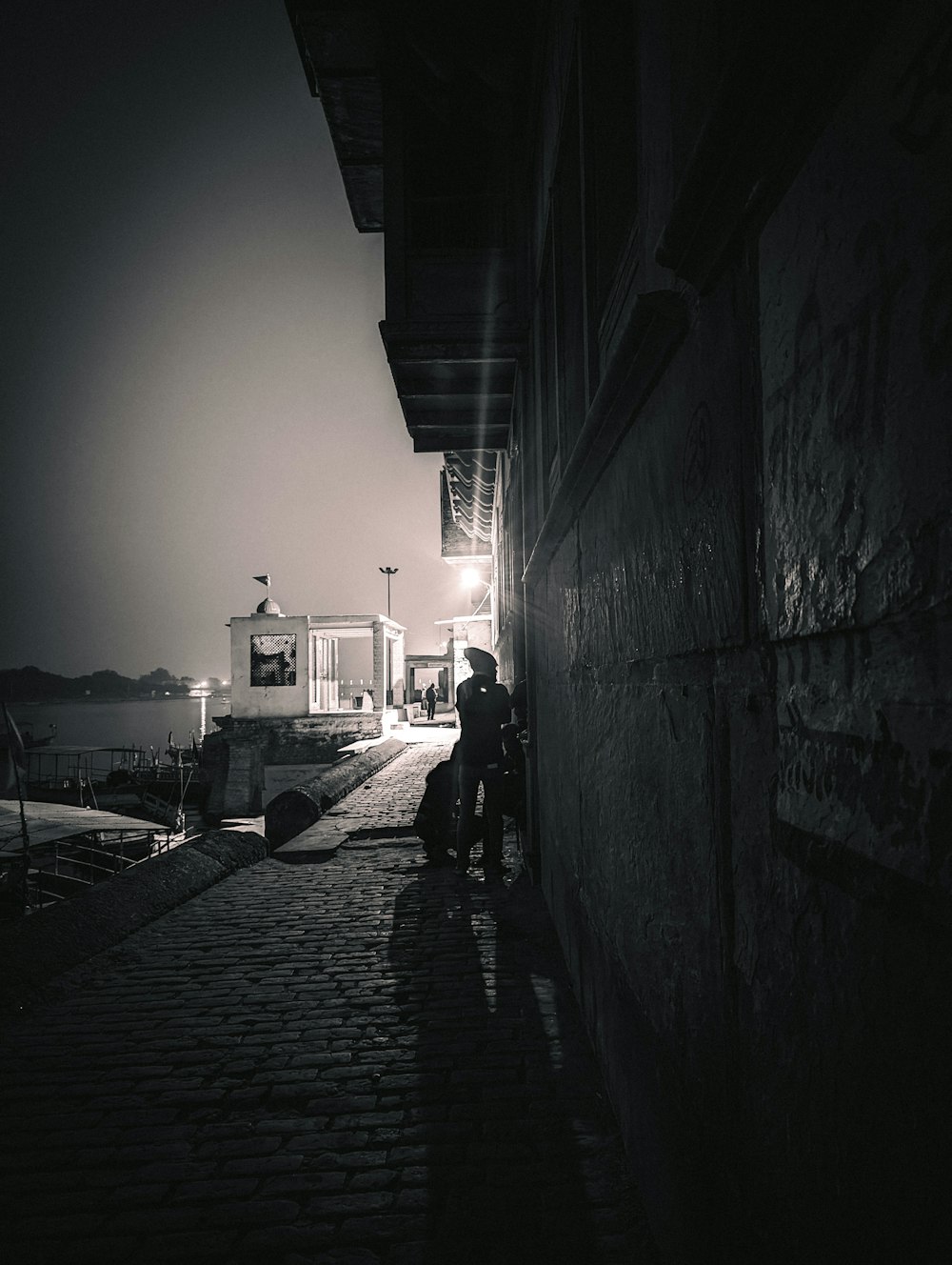 a person standing on a cobblestone street at night