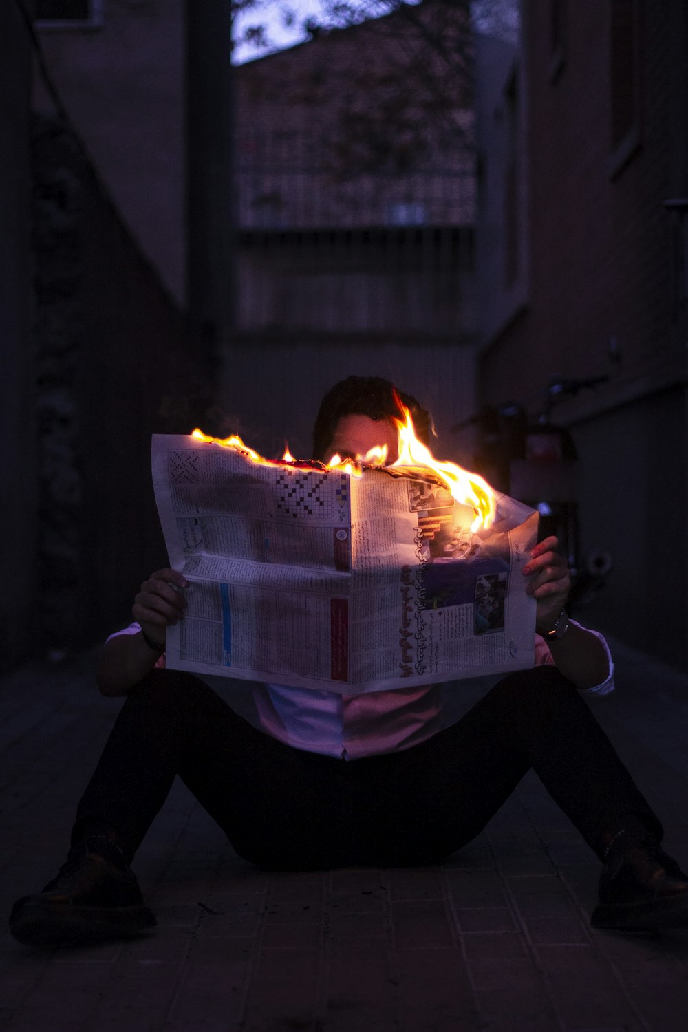 a person sitting on the ground reading a newspaper