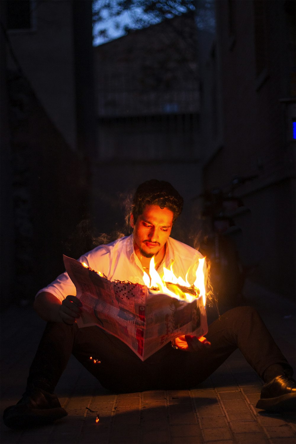 a man sitting on the ground reading a newspaper