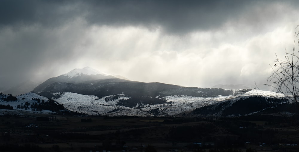 a mountain covered in snow under a cloudy sky