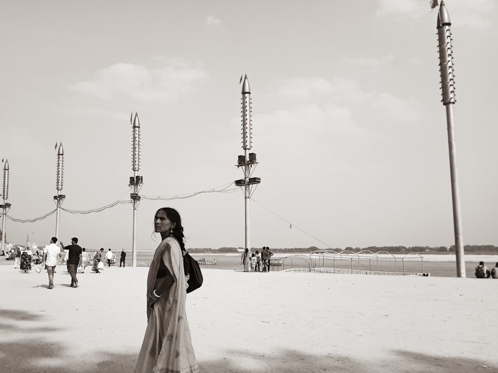 a woman standing on a beach next to tall poles