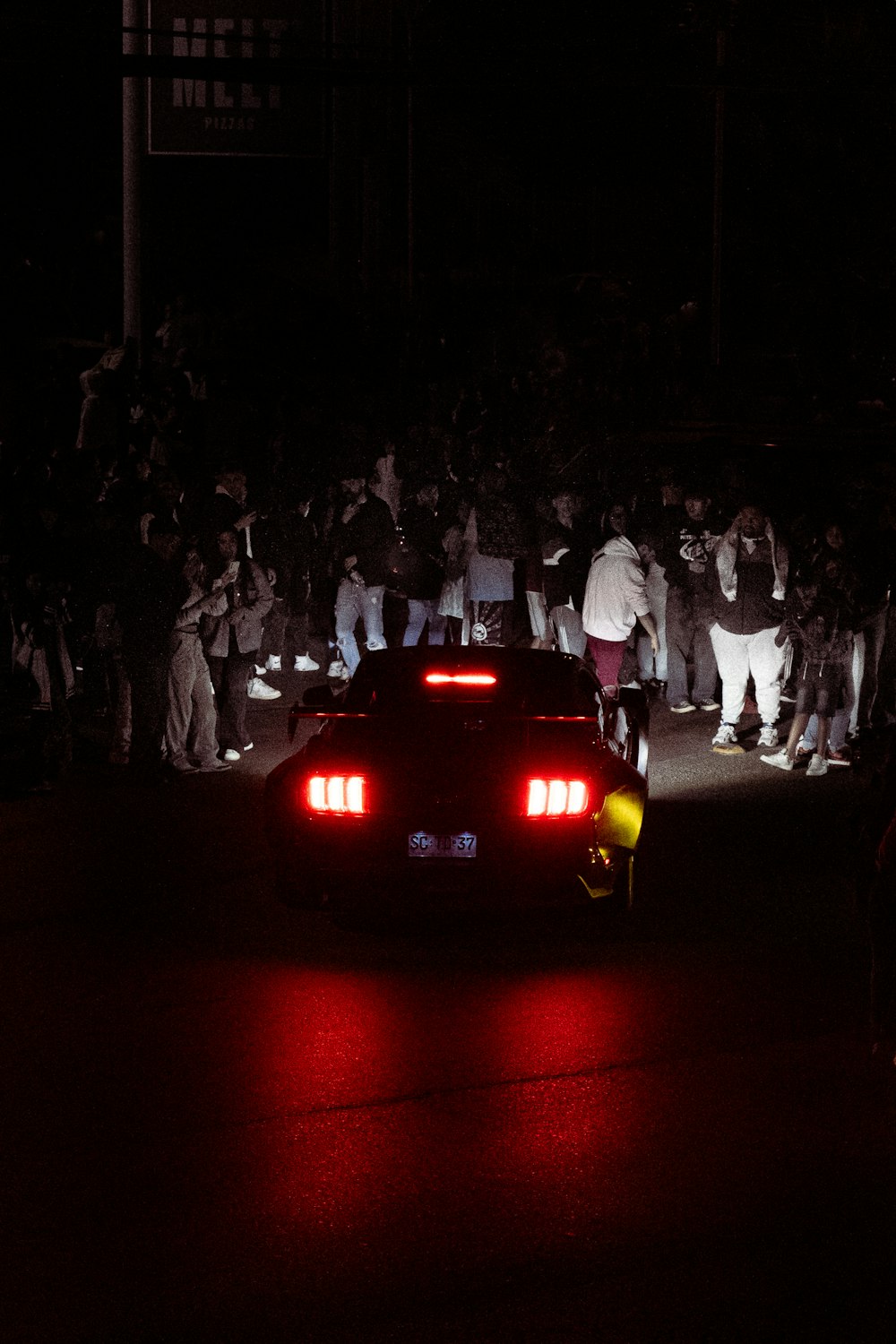 a red car driving down a street at night