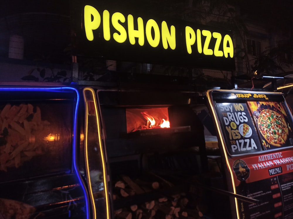 a pizza oven with a neon sign above it