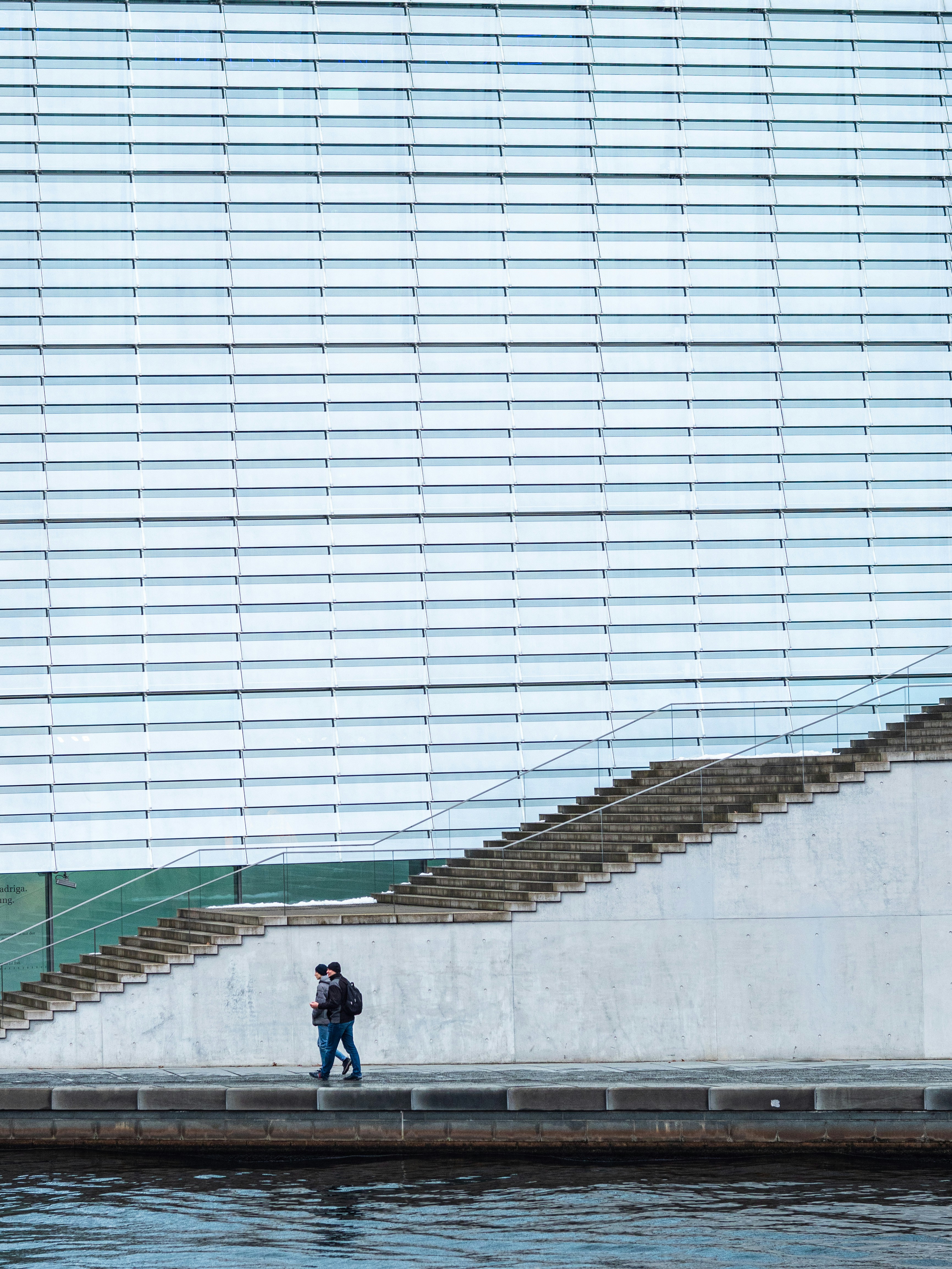 Un hombre caminando por una acera junto a un cuerpo de agua