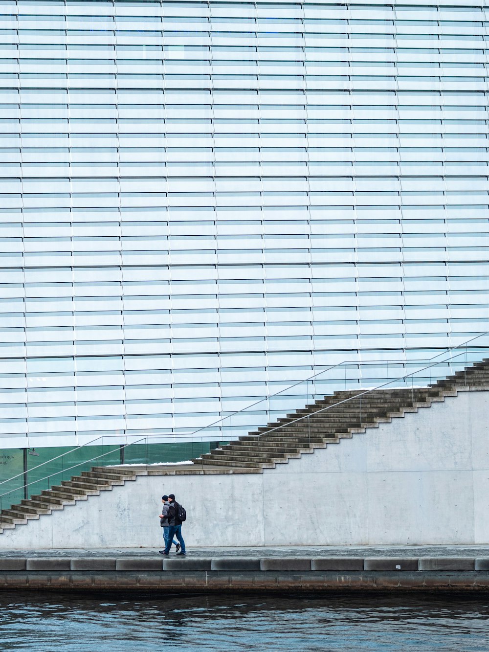 a man walking down a sidewalk next to a body of water