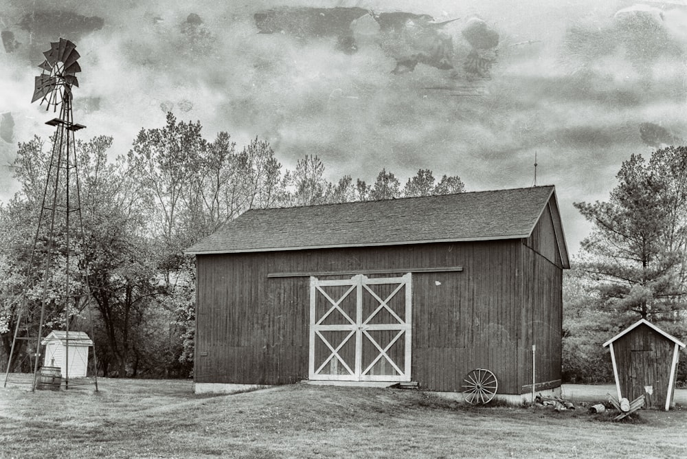 a black and white photo of a barn and a windmill