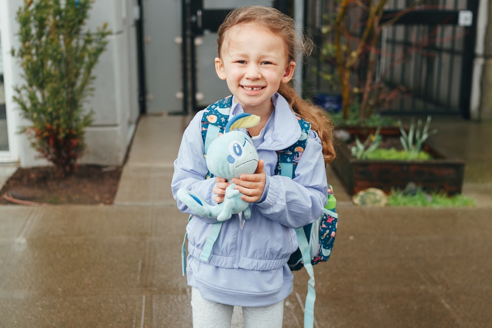 a little girl is holding a stuffed animal