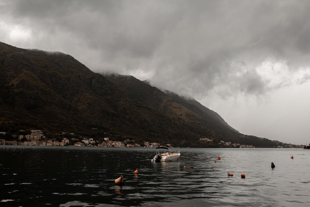 a boat floating on top of a lake under a cloudy sky
