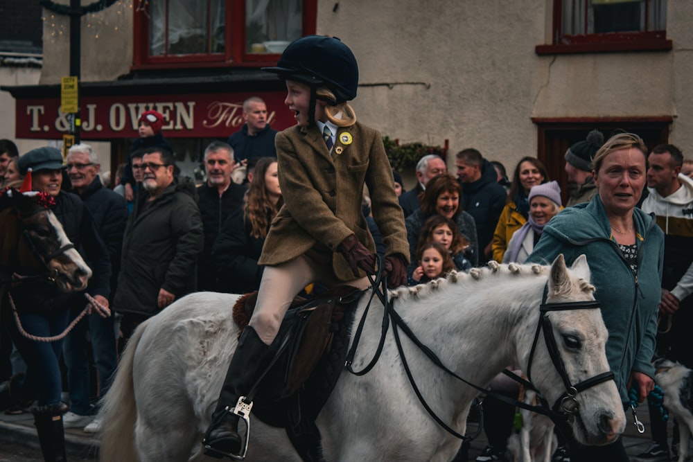 a woman riding on the back of a white horse