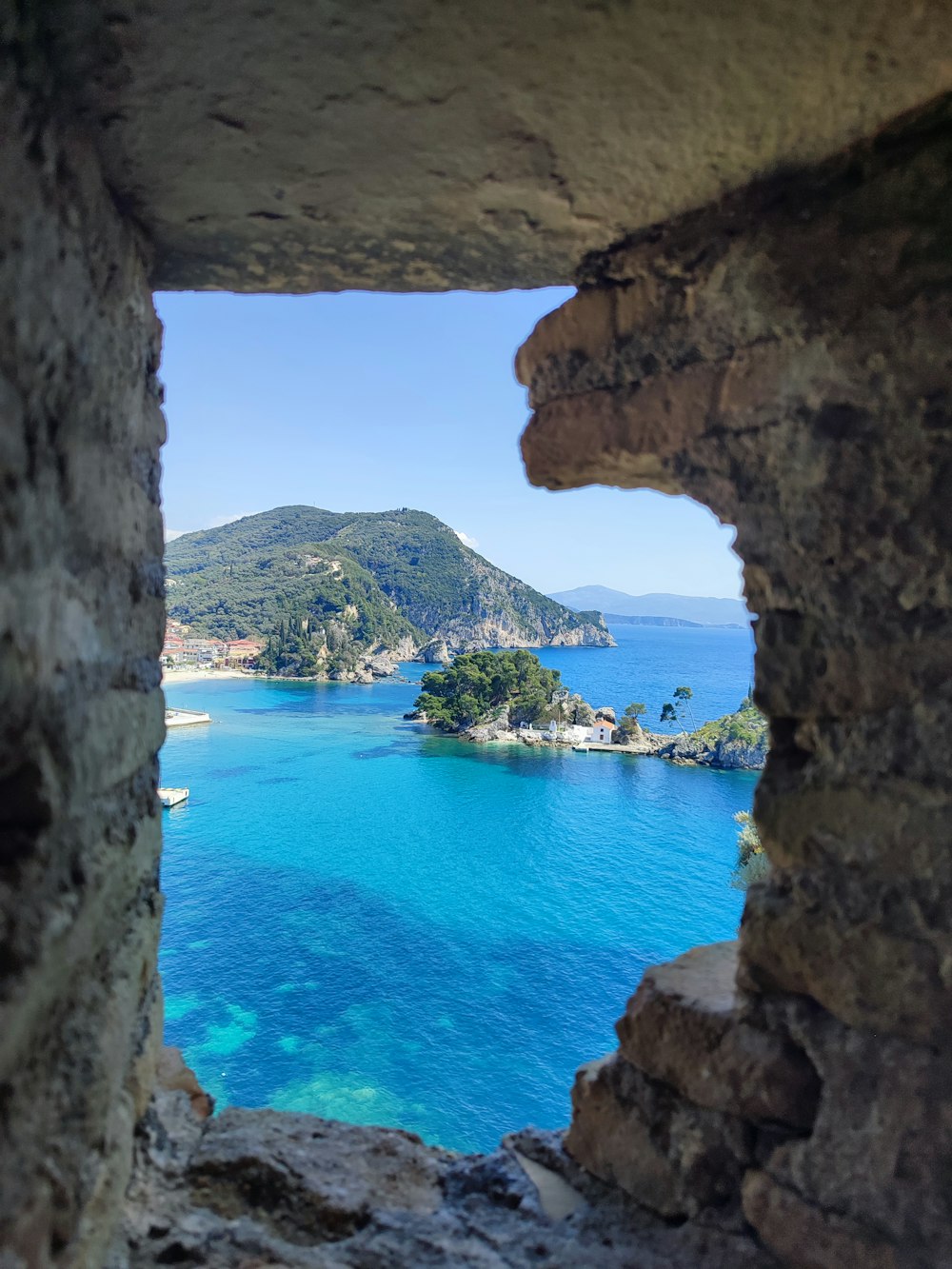 a view of a body of water through a hole in a stone wall