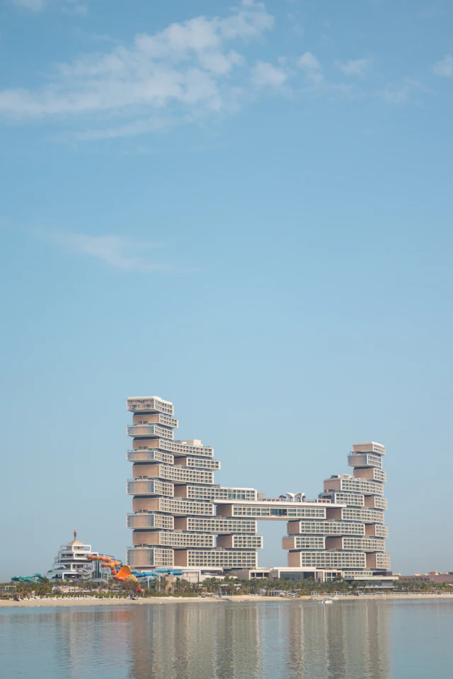 Atlantis The Royal's twin stacked towers linked by a sky bridge, reflected in the sea at dusk.