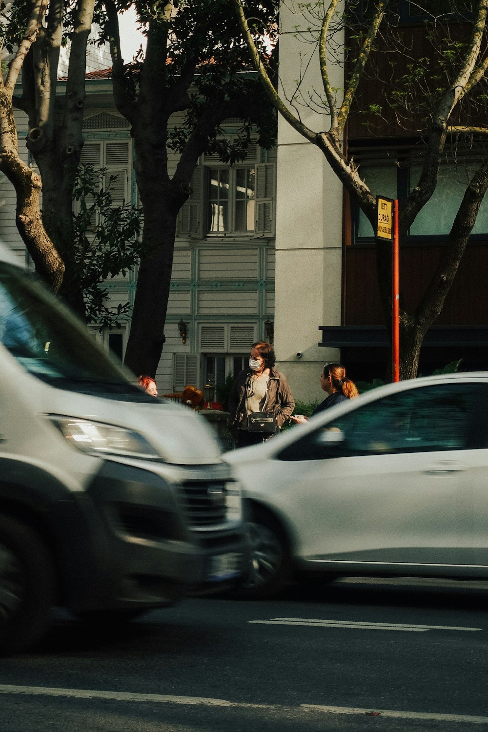 a group of cars driving down a street next to a tall building