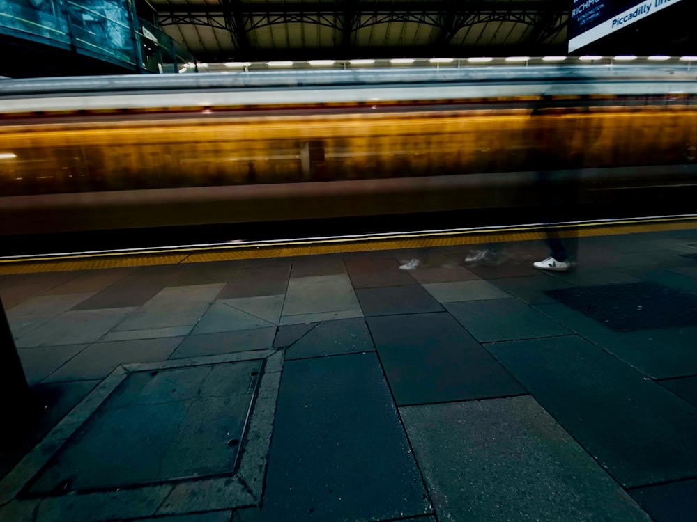 a person standing on a sidewalk next to a train