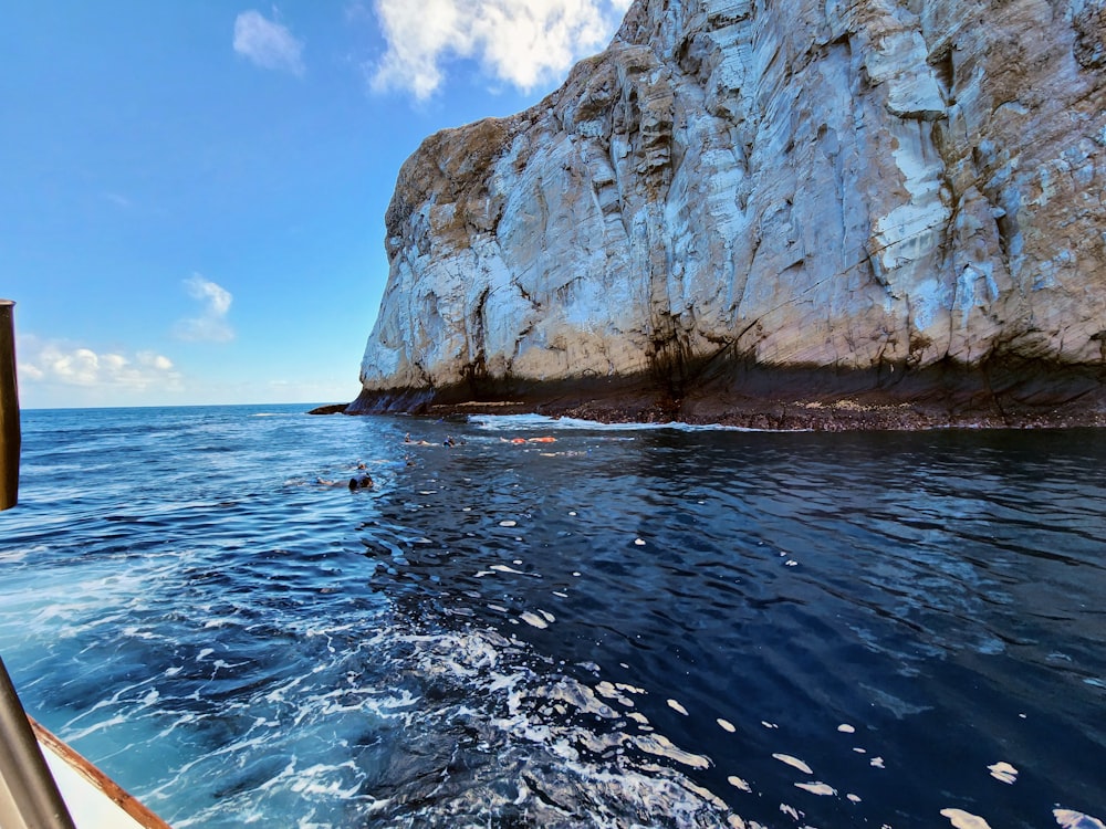 a boat traveling past a large rock formation in the ocean