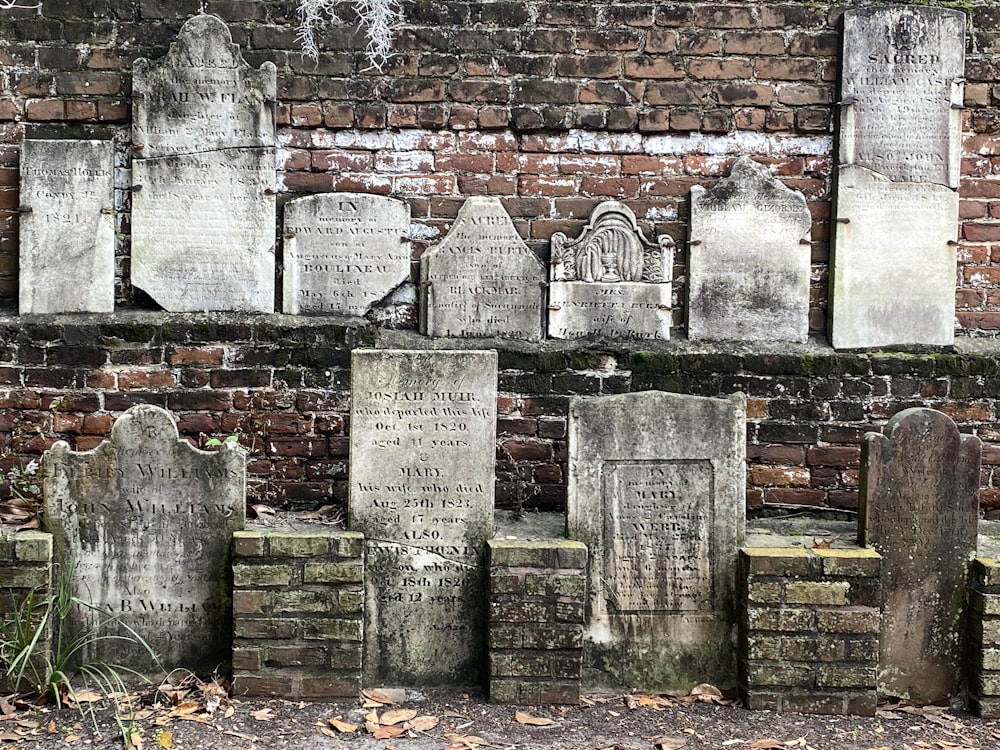 a bunch of headstones on a brick wall