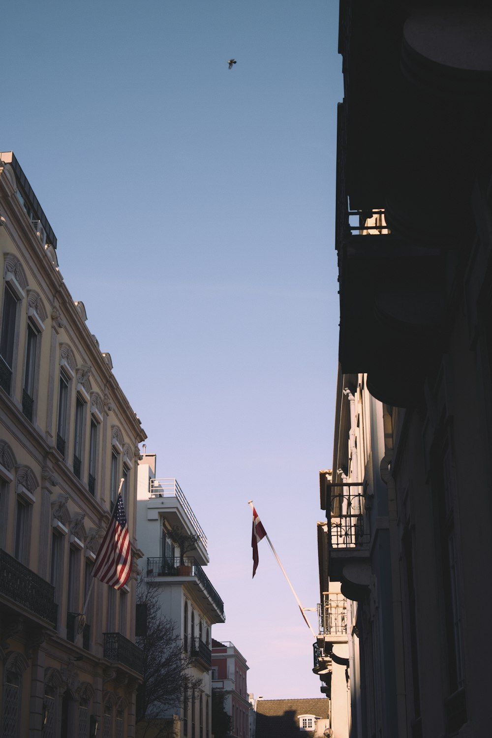 a flag flying in the air next to a row of buildings