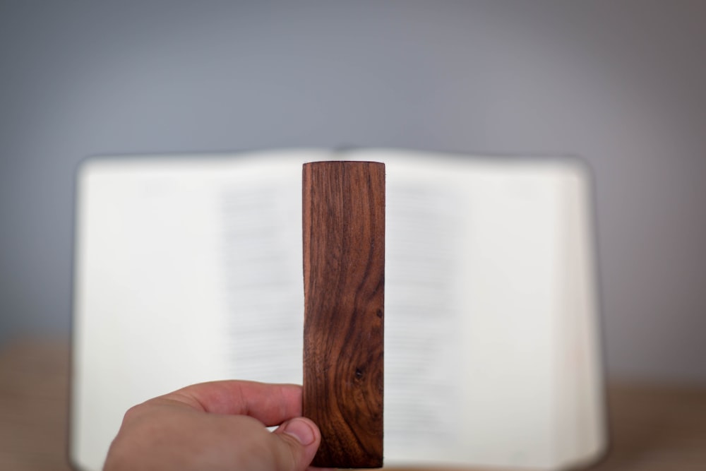 a hand is holding a wooden object in front of an open book