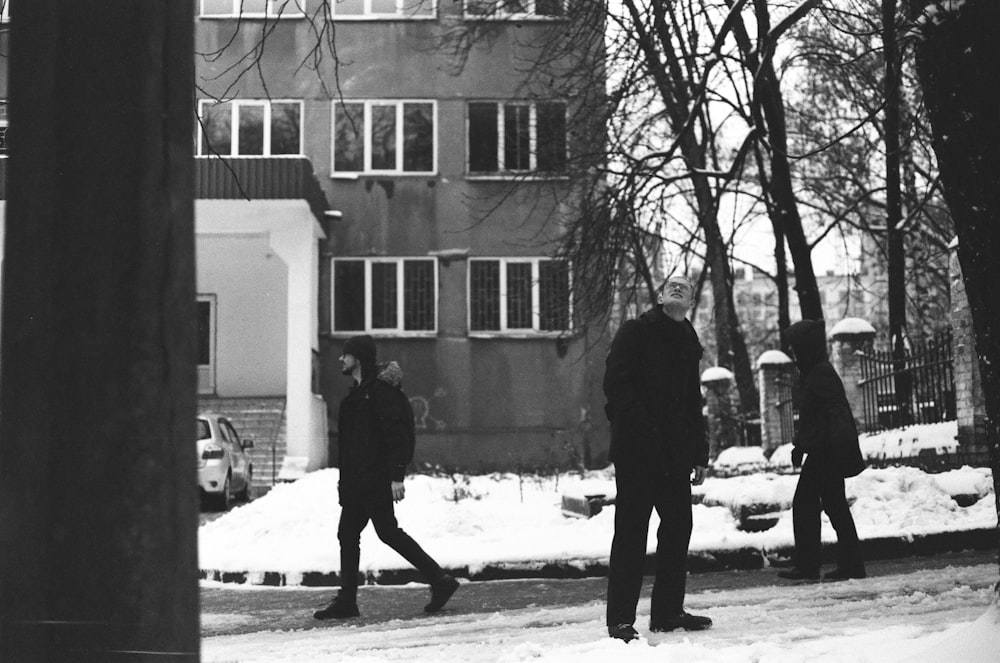 a black and white photo of people walking in the snow