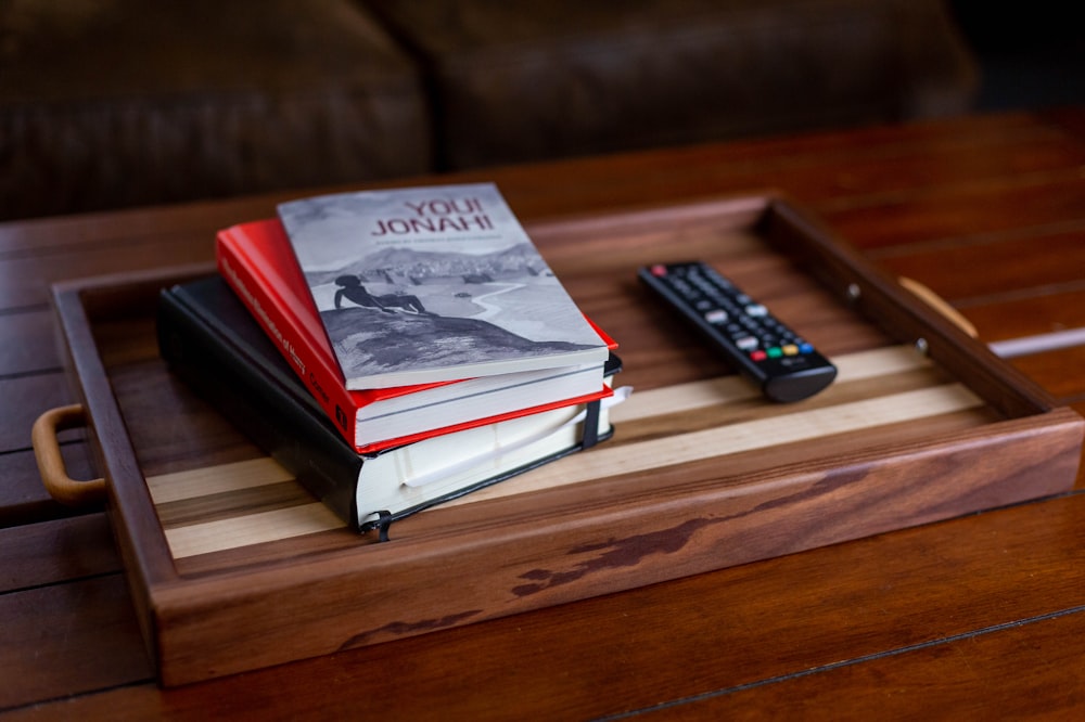 a stack of books sitting on top of a wooden tray